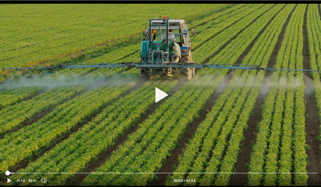 Un tracteur pulvérise des pesticides sur un champ.