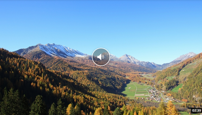 Une vidéo avec vue sur une vallée avec des arbres et des montagnes en arrière-plan.