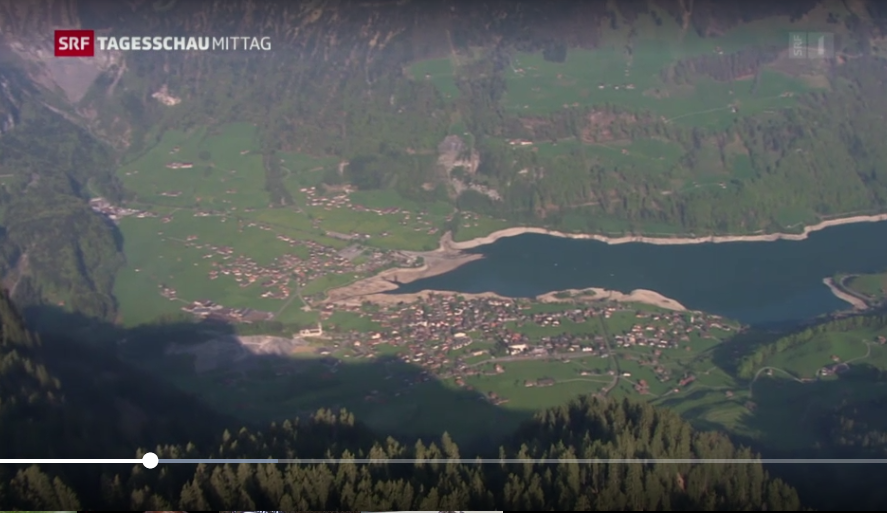 Vue aérienne des Alpes suisses avec lac et village.
