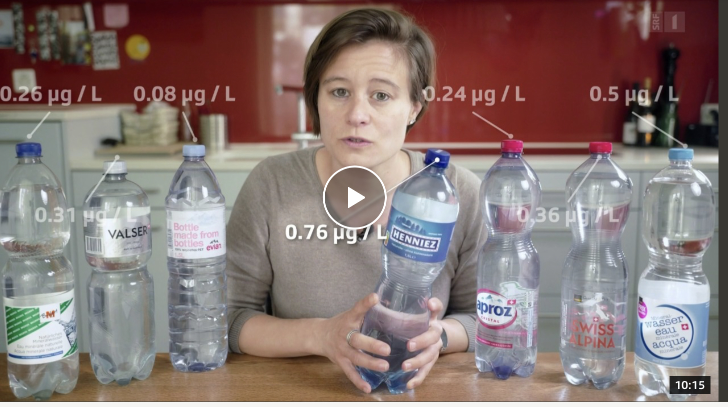 Une femme est assise à une table devant plusieurs bouteilles d'eau en plastique.